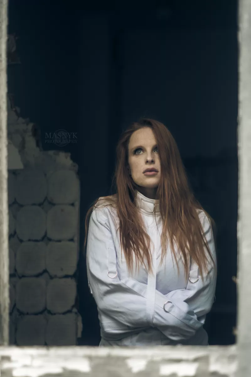Redhead in straitjacket bondage by window